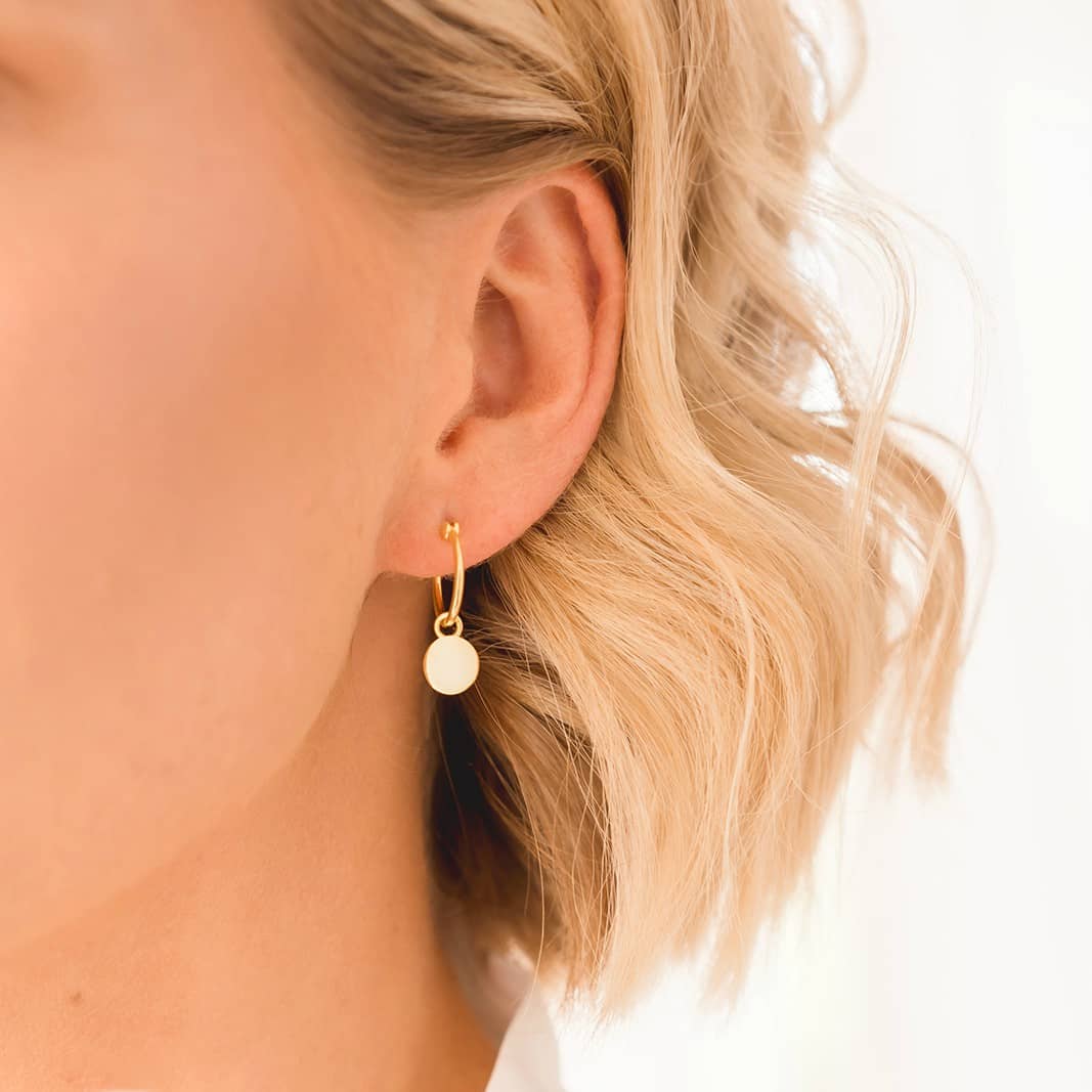yellow gold mini hoop disc earrings on ear