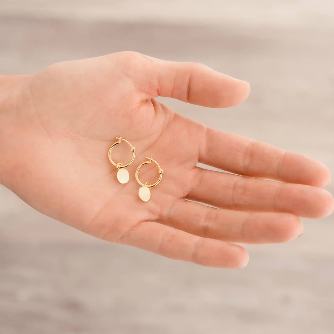 yellow gold mini hoop disc earrings in hand